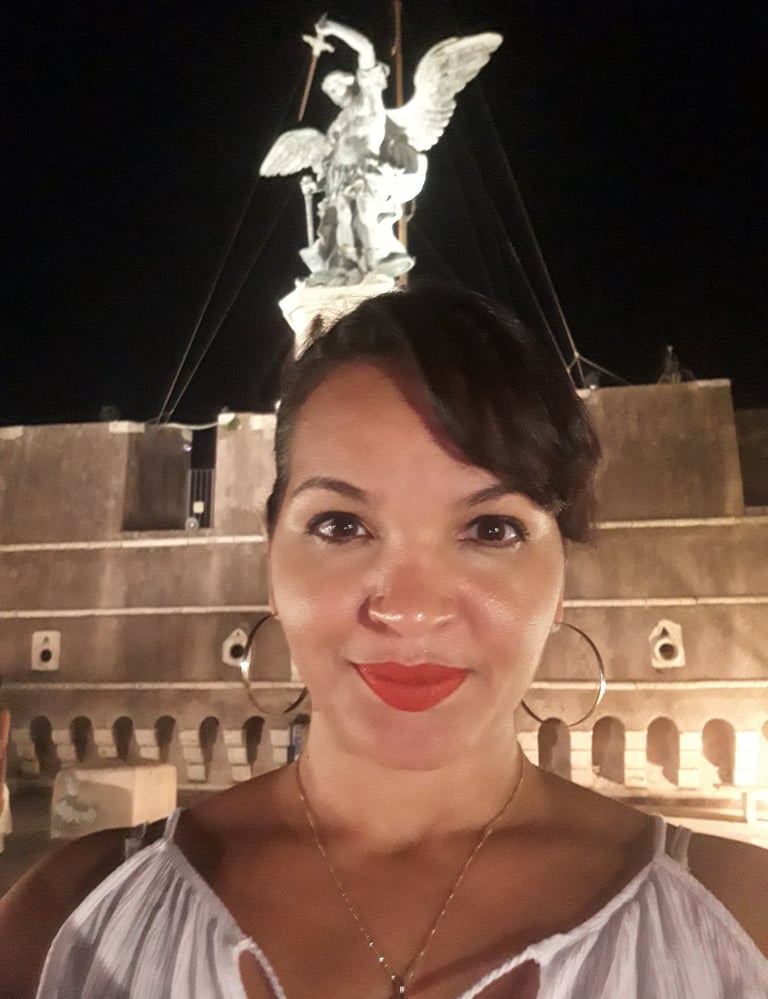 imagem da advogada Bianca Santos em frente a estátua de um anjo que fica no topo do castelo sant angelo em Roma na Itália.