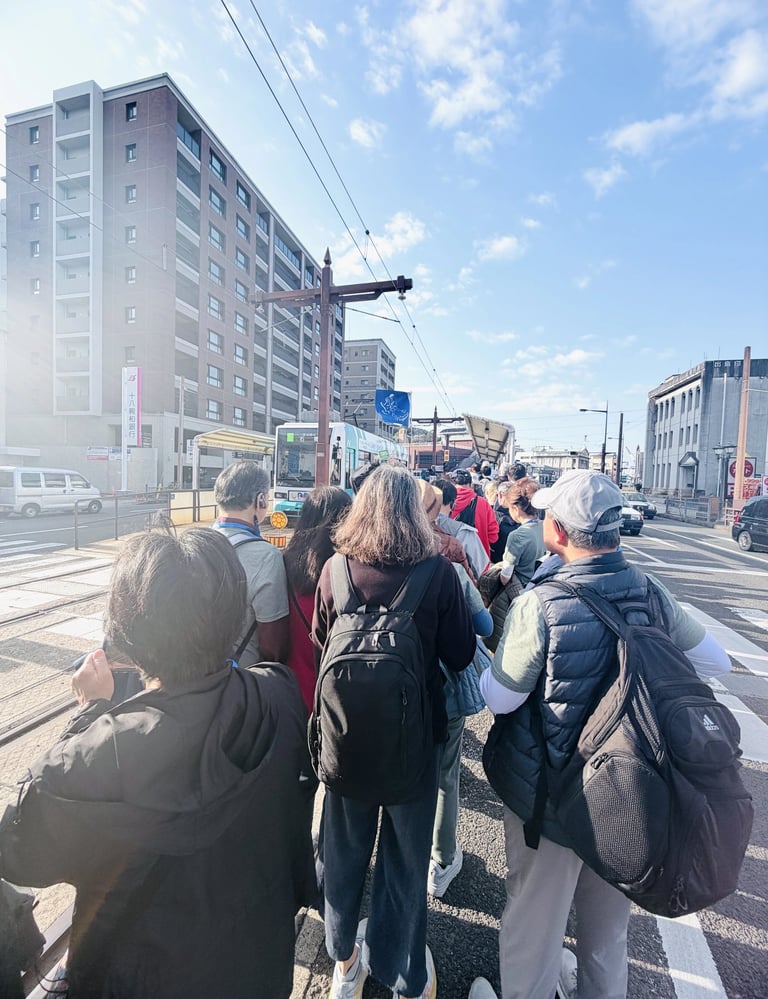 Crowded tram stop in Nagasaki with many tourists waiting to board during peak travel time