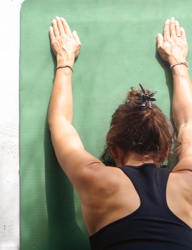 Close-up of yoga teacher in child pose on green mat with arms forward, yoga and pranayama