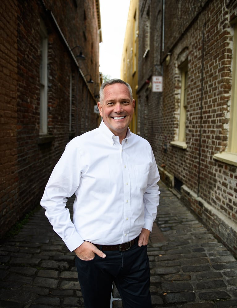 a man in a white shirt and jeans standing in an alley alleyway