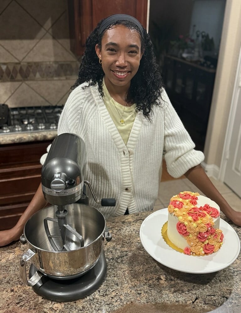 a woman in a white sweater and a cake on a counter