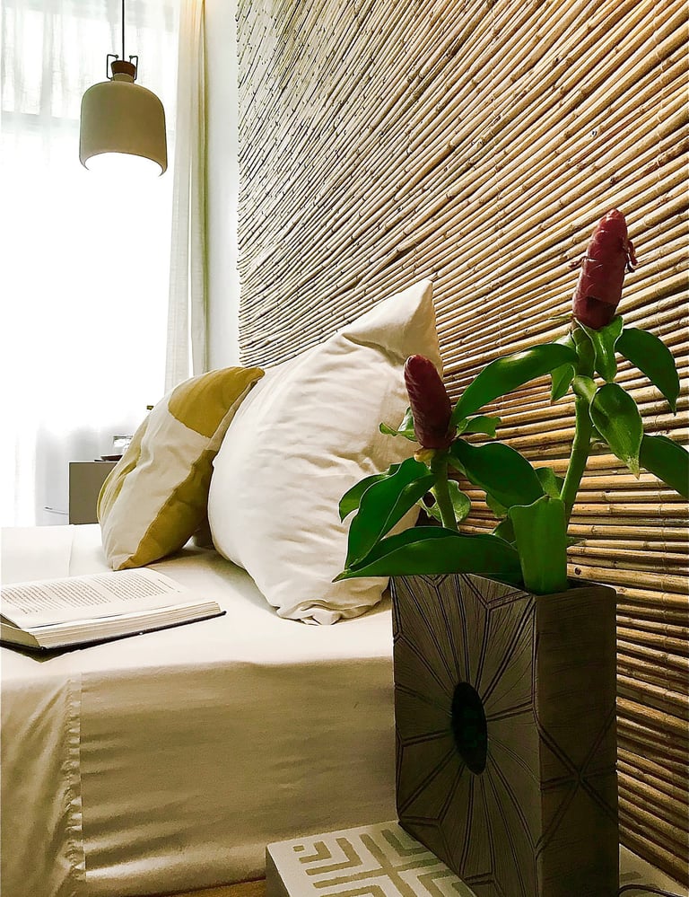 a vase with a flower in a vase on a bed