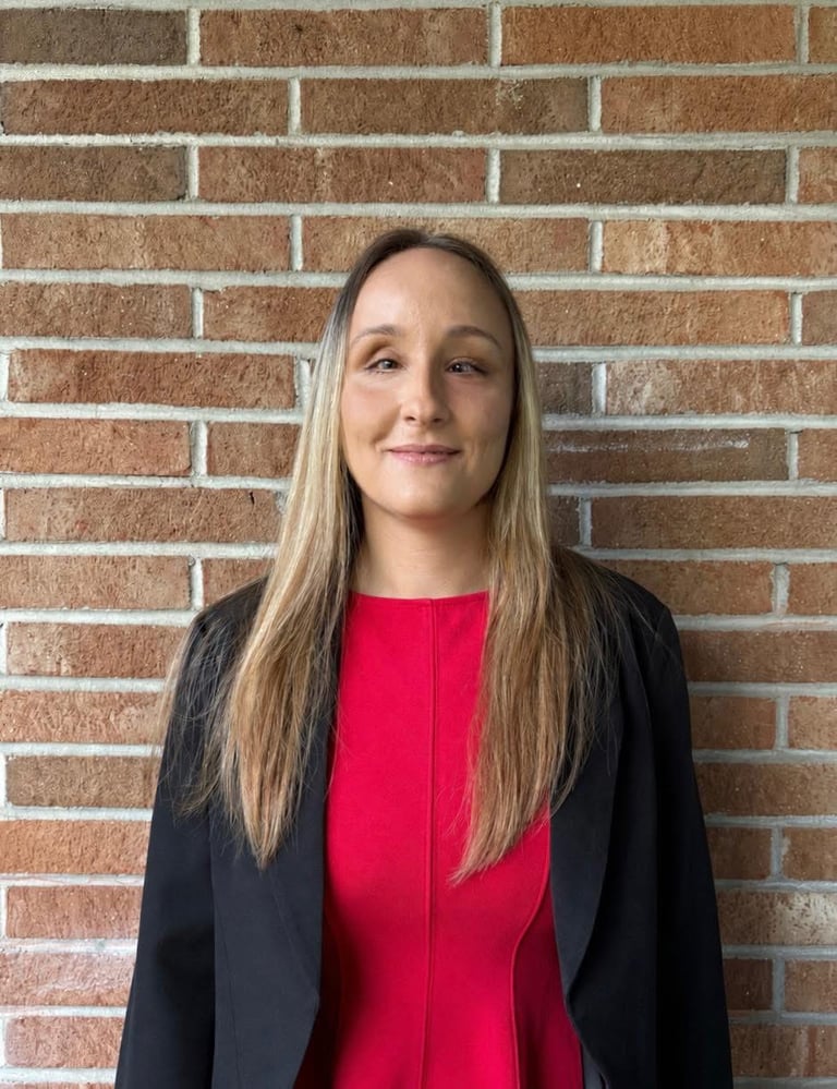 Founder Zhenya wears business attire and poses for a photo in front of a brick wall.