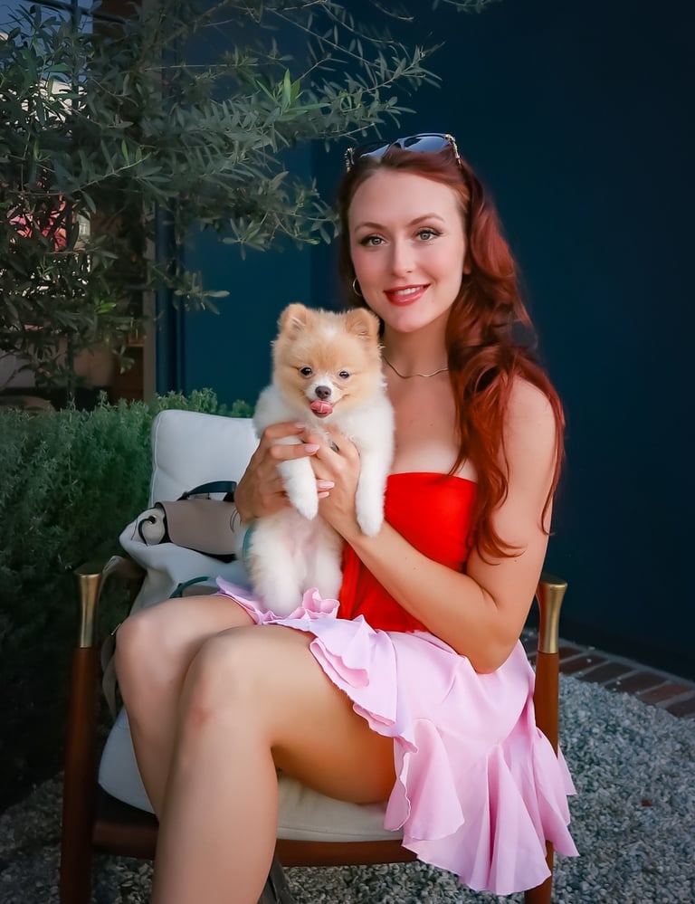 Founder Megan Patricia Keyser holding Liebe the Pomeranian in a West Hollywood outdoor lounge.