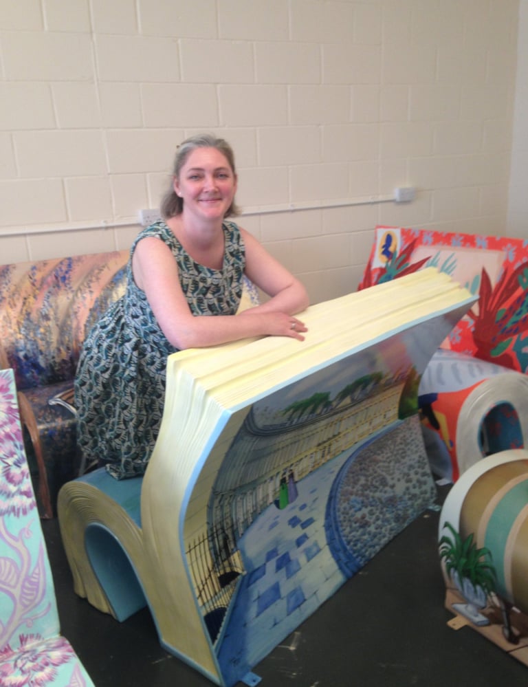 Laura Fearn kneeling on her Sitting With Jane bookbench