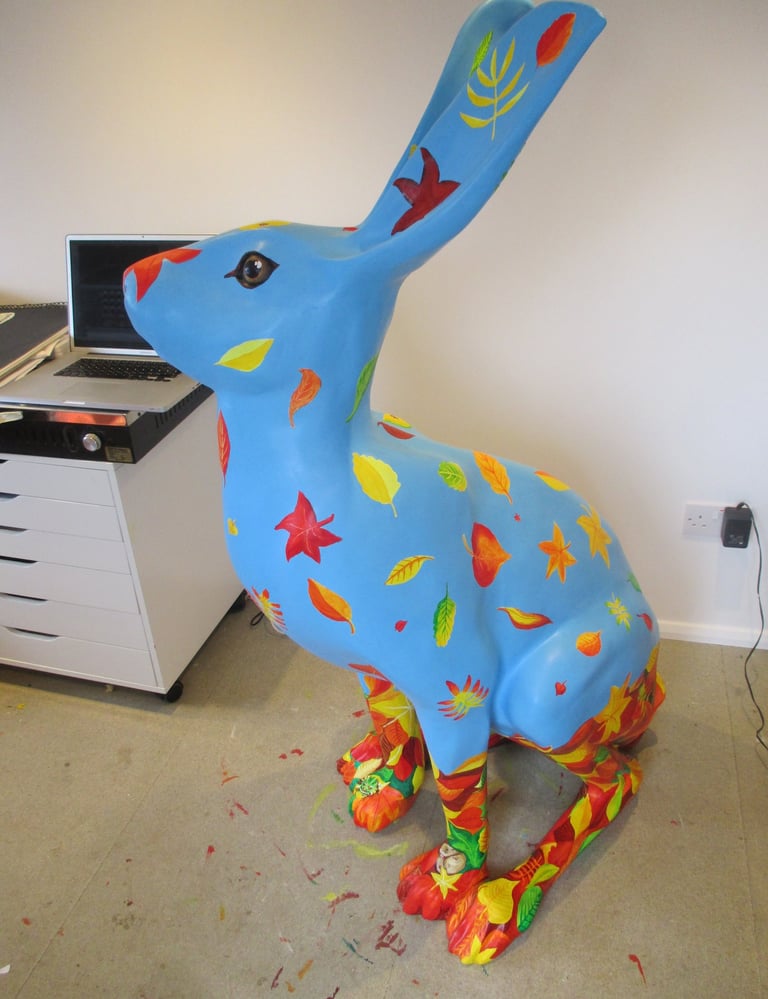 A hare sculpture with autumn leaves and wildlife painted by Laura Fearn
