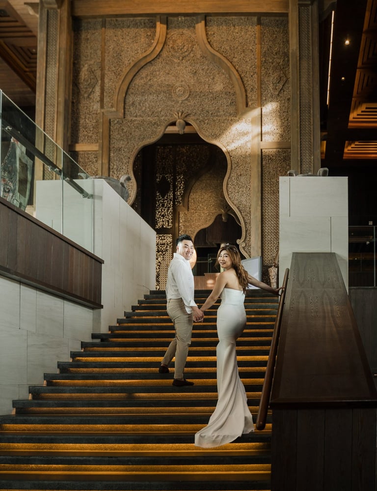 Couple walking down the grand staircase during a luxury prewedding photoshoot at Apurva Kempinski Bali