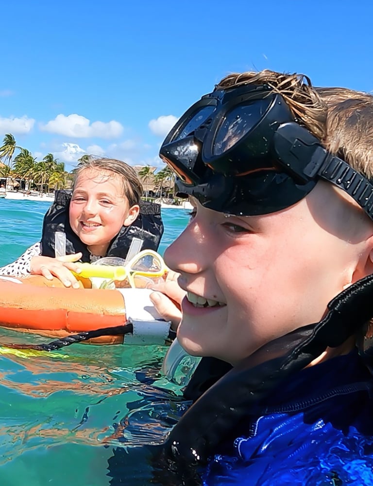 a boy and girl in wetsuits in the water