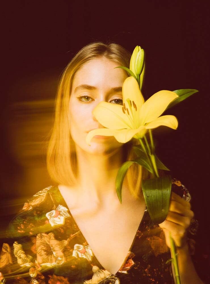 a woman holding a flower in front of a mirror