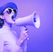 a woman in a hat and sunglasses is holding a megaphone