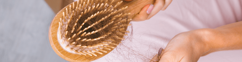 Spazzola in legno con capelli caduti, rappresentazione della perdita di capelli e dell'importanza de