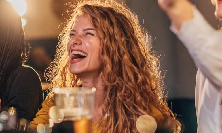 a woman is laughing and holding a beer