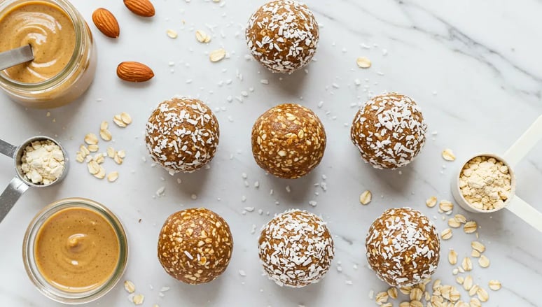 No-bake protein energy balls with shredded coconut, surrounded by oats, almonds, and peanut butter.