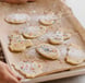 a person holding a cookie cookie on a baking sheet