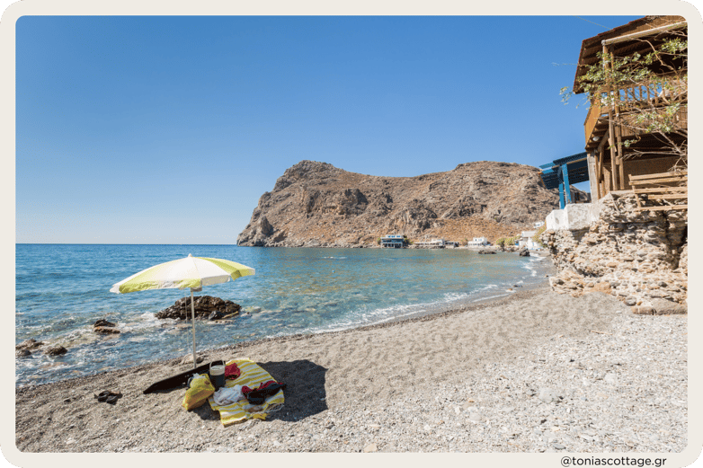 An umbrella and towel left on the peaceful Lendas Beach, Crete, Greece