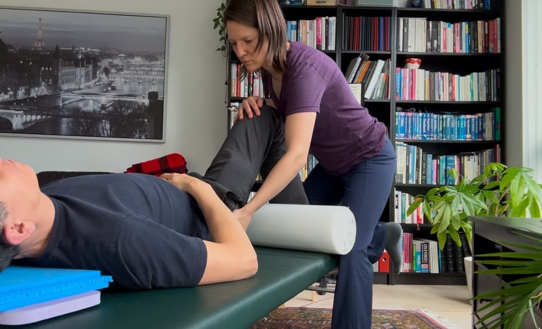A Feldenkrais Teacher is giving a Functional Integration©️ session to a man.