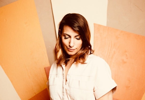 a woman in a white shirt and jeans standing in front of a wall