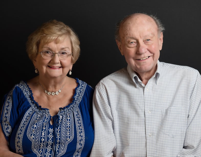 a man and woman sitting next to each other smiling holding hands