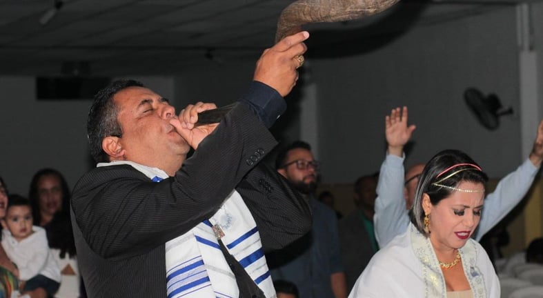 a man blowing a horn horn while a woman in a white dress