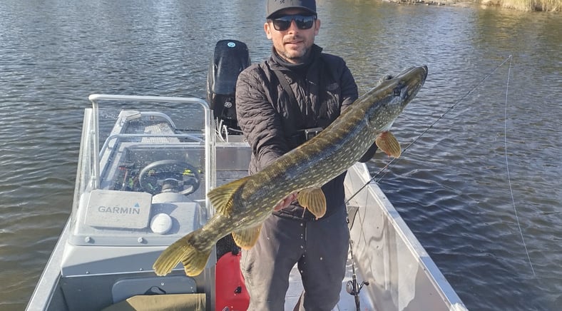 un pêcheur est sur un bateau de pêche , le bateau est un "linder 460". il a beau brochet en suede. .