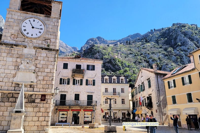 Clock tower on the main square in medieval town of Kotor with steep ⛰  as a backdrop