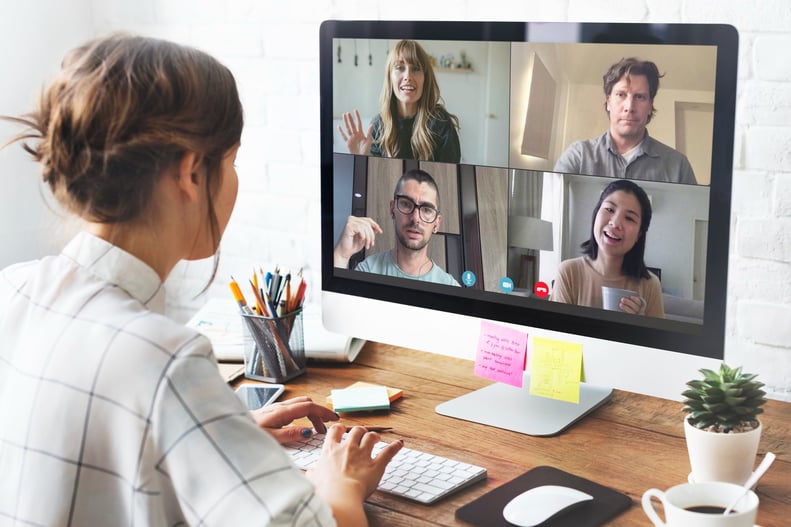 a woman sitting at a computer screen with a video chat