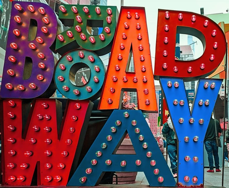  brightly colored "BROADWAY" sign with illuminated bulbs stands in Times Square, New York City