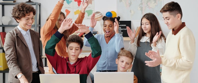 a group of people standing around a table with laptops