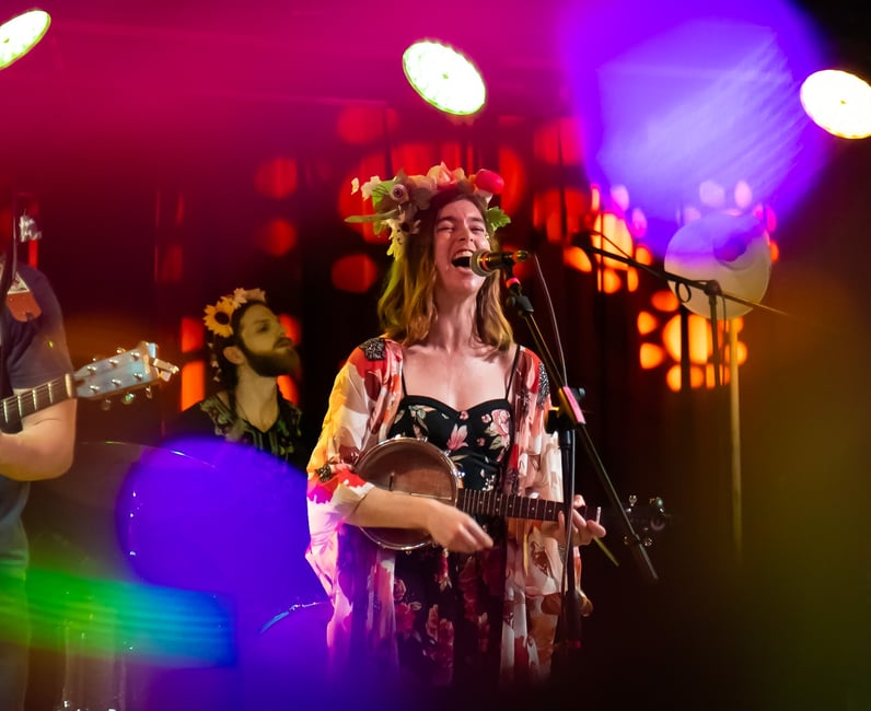 a woman singing and playing guitar in a band