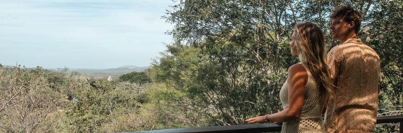 a man and woman standing on a balcony with a view of the ocean