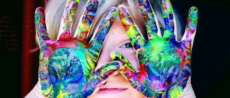Un enfant joyeux en art-thérapie avec des mains colorées pour créer son œuvre d'art