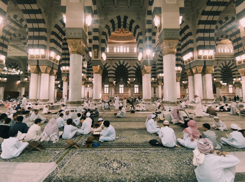 Interior of Masjid Nabawi with striped pillars and worshippers