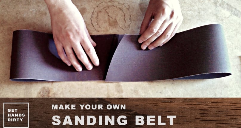 Hands around a piece of sandpaper roll in the shape of a sanding belt