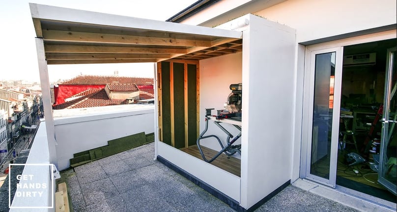 An outdoor shed in a small balcony. Grass over the roof.