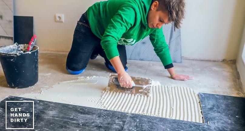 Applying cement to the floor in order to install the black ceramic tiles