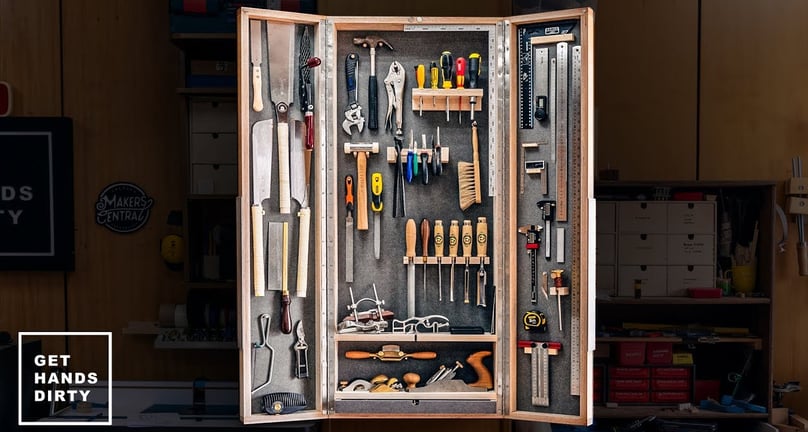 Image of cabinet full of different tools, such as rulers, chisels, saws and hand planes.
