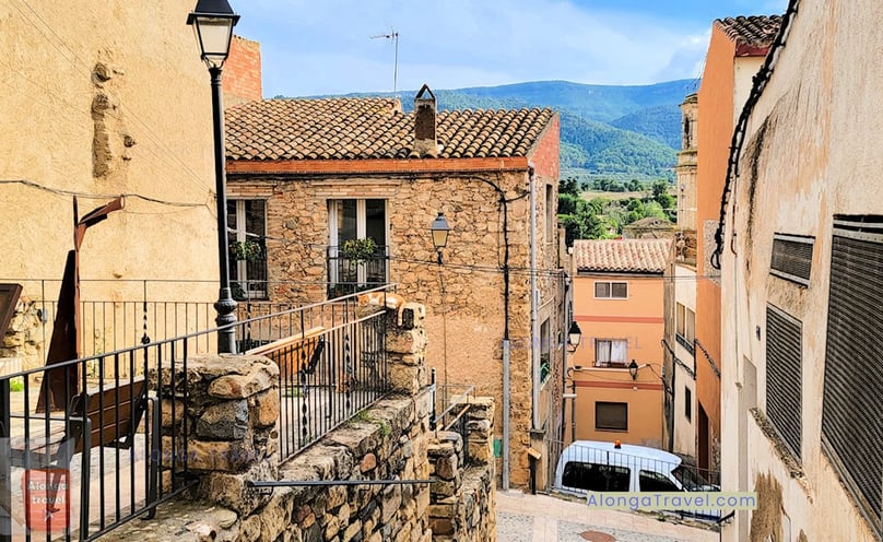 A cat enjoying cozy nap on a tall post on medieval square overlooking Church of Sant Miquel Espluga