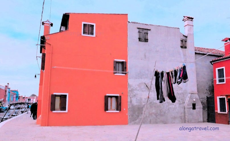 A clothing line in front of corral and gray old buildings of an undefined shape in Italy