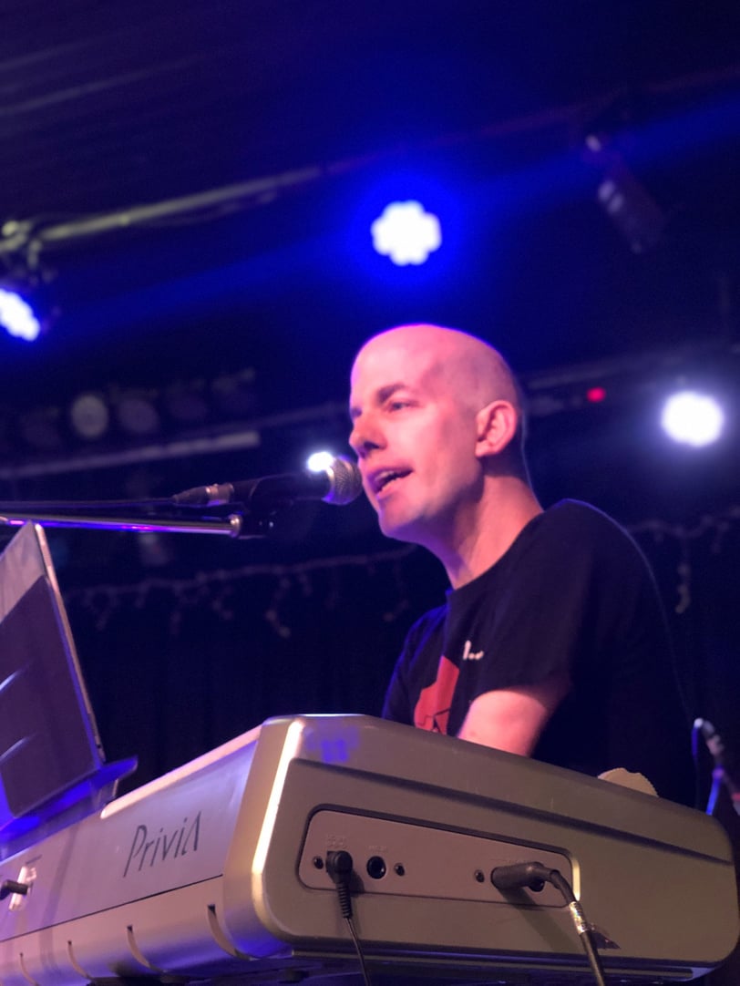 Yoav Rokach Penn wearing a black T-Shirt, Playing the piano and singing in front of a microphone.