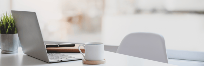 clean minimalist office desk with a laptop, a mug and a notebook with a pen.