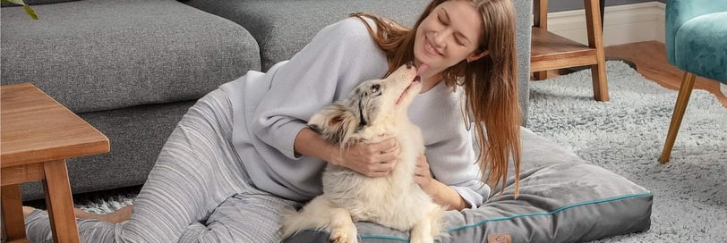 a woman sitting on a dog bed with her dog