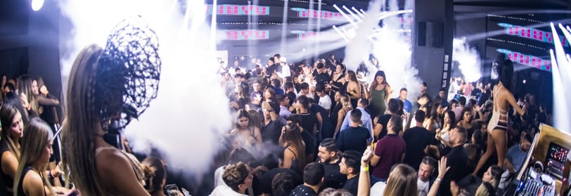 a crowd of people standing around a dj booth, rico sanchez performance at La V in Miami