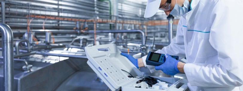 a man in a white lab coat and gloves is holding a laptop computer
