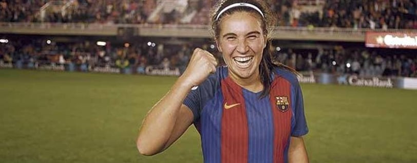 a woman in a soccer uniform is smiling and holding a cell phone