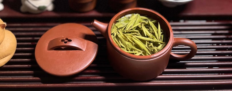 teapot and lid placed on a wooden tea table, with tea leaves inside the pot