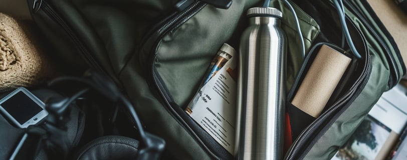 An open dark green travel bag contains a stainless steel water bottle.