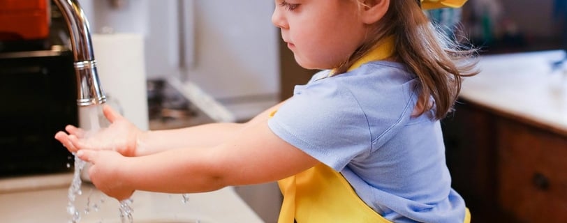 Little girl washing hands in kitchen sink