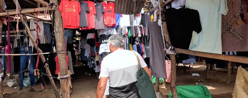 a man walking through a market with clothes on display