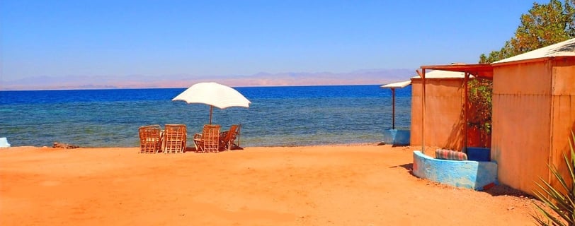 a beach with chairs and umbrellas on the sand
