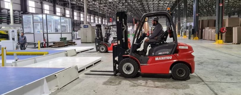a forklift truck in a warehouse with a man in the background